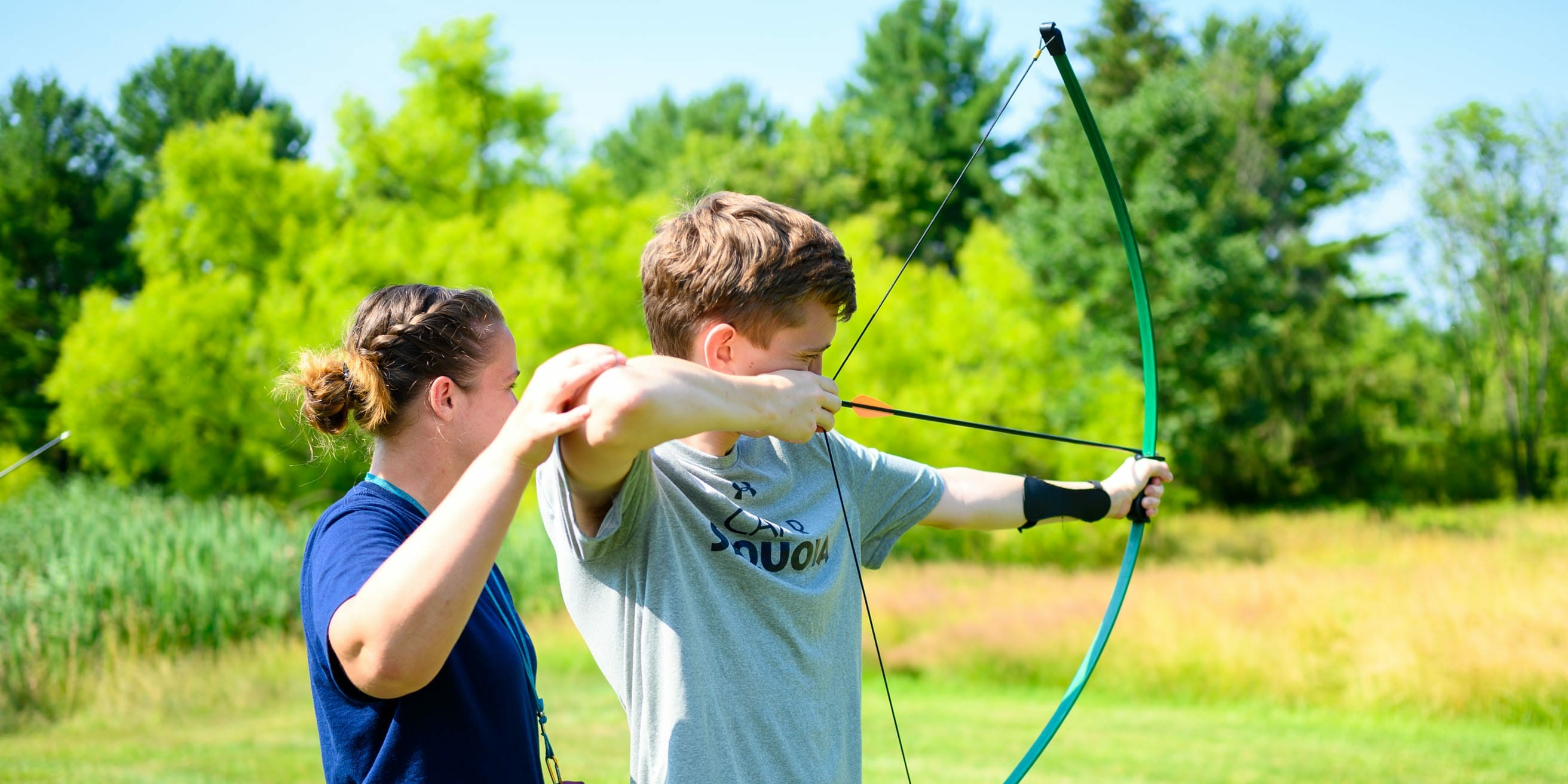 Archery instructor helping camper