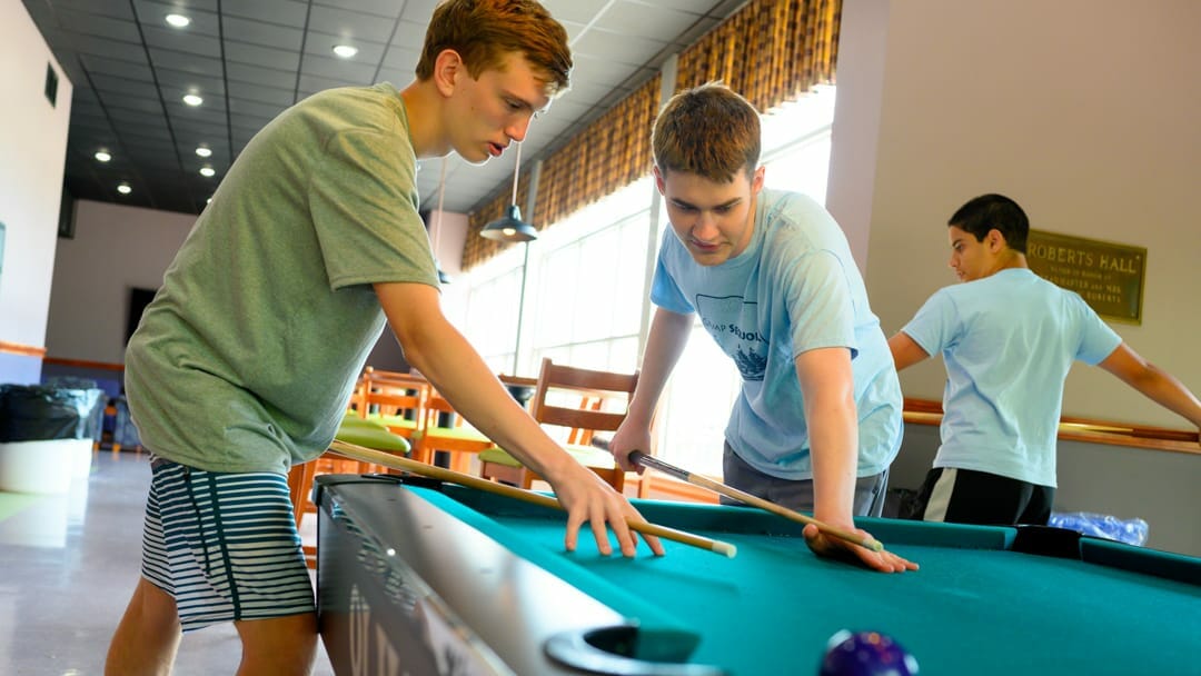 Two boys playing billiards