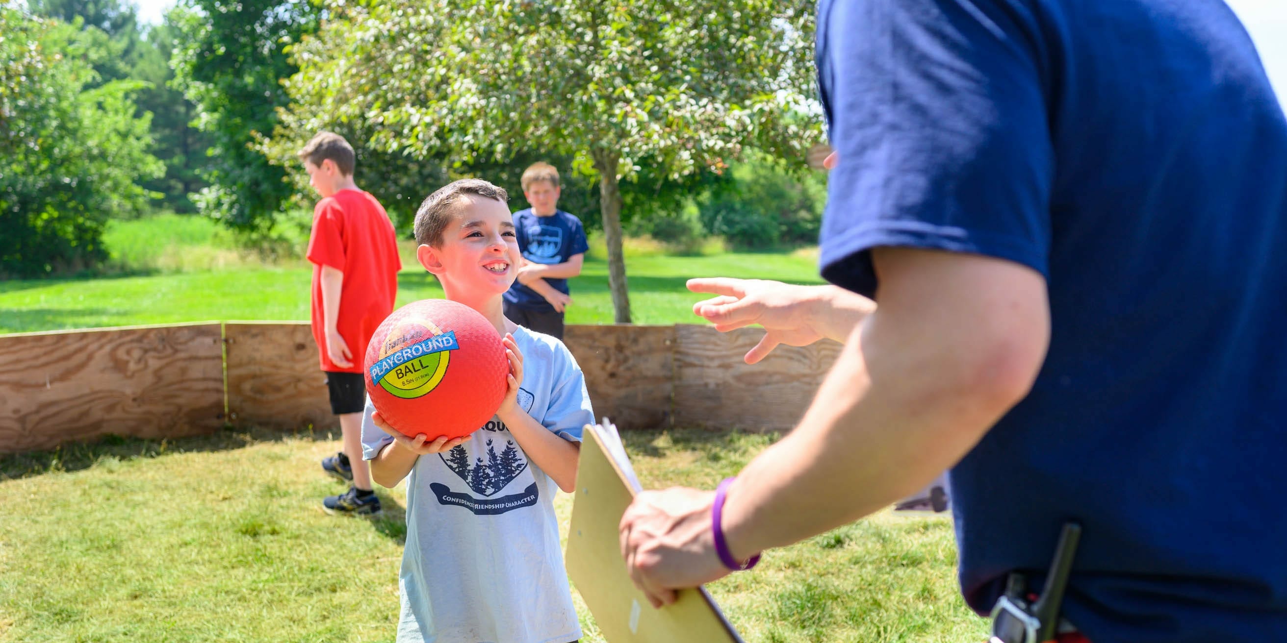 Camper with gaga ball smiling at staff