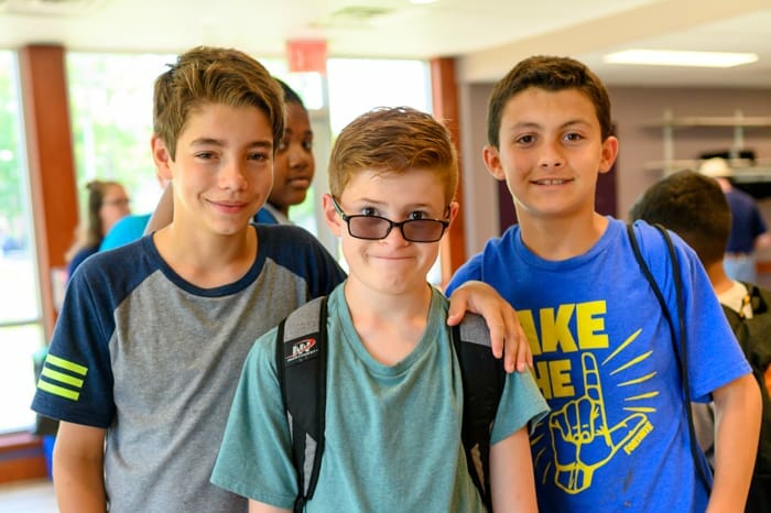 Three boys smiling by dining hall